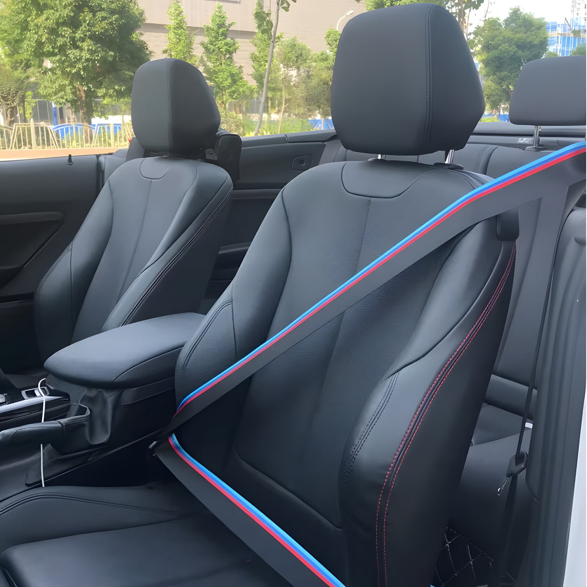 Black seat belt with a blue and red stripe fitted to a car seat