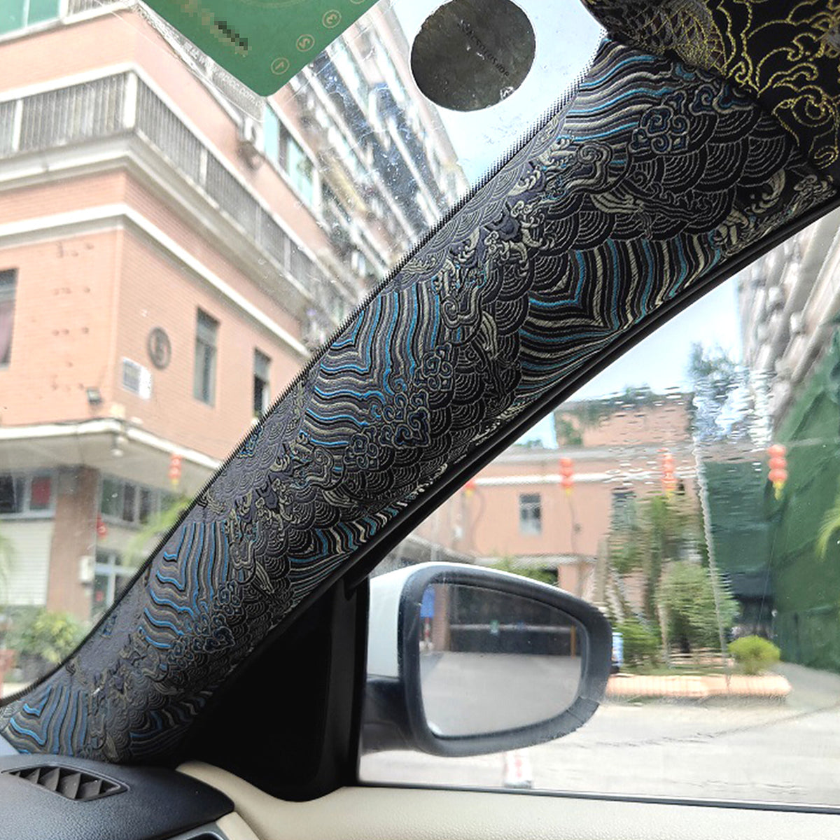 Blue embroidered wrap on a car A-pillar beside the windscreen